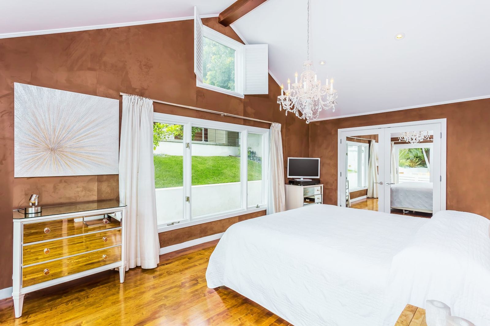 Primary bedroom with copper accent wall and chandelier